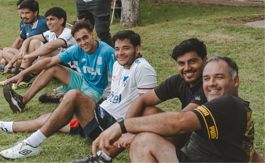 Foto de varones sentados en el pasto sonriendo