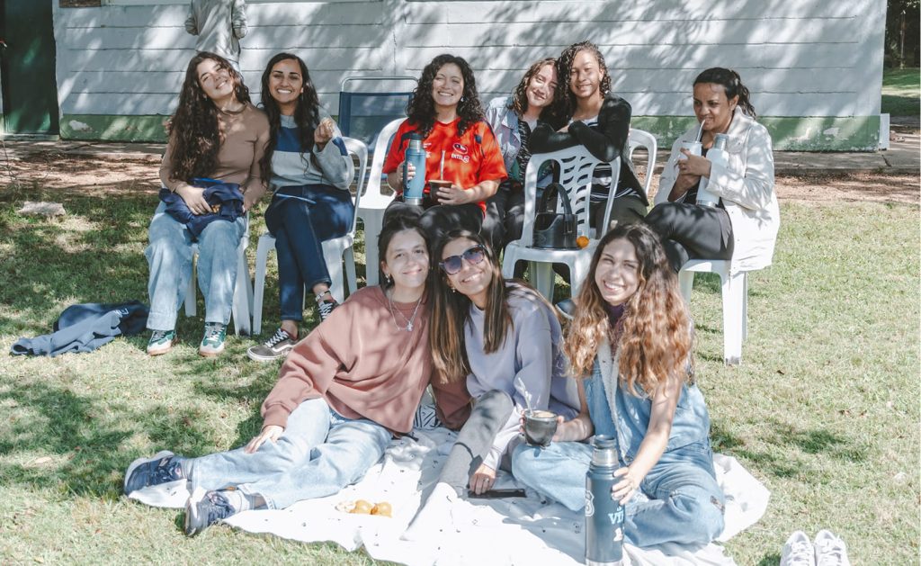 Foto de mujeres sentadas en el pasto sonriendo
